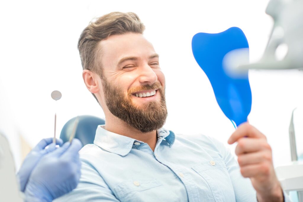 patient looking at his beautiful smile sitting at the dental chair.